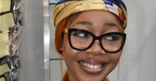 A lady putting on Carolina Herrera frame with a smile| SpecSMART Eye Clinic Ikeja 