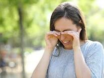 Woman outdoors rubbing her itchy eyes, possibly due to allergies or irritation| SpecSMART Eye Clinic Ikeja