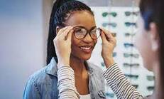 Woman trying on eyeglasses with help from an optician| SpecSMART Eye Clinic Ikeja