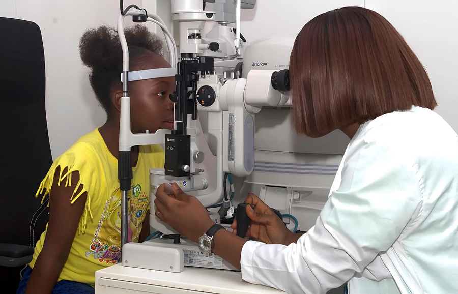 Optometrist using a TOPCON SL-D301 slit lamp to check young girls eyes